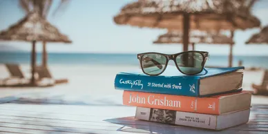 Beach with stack of reading books and sunglasses